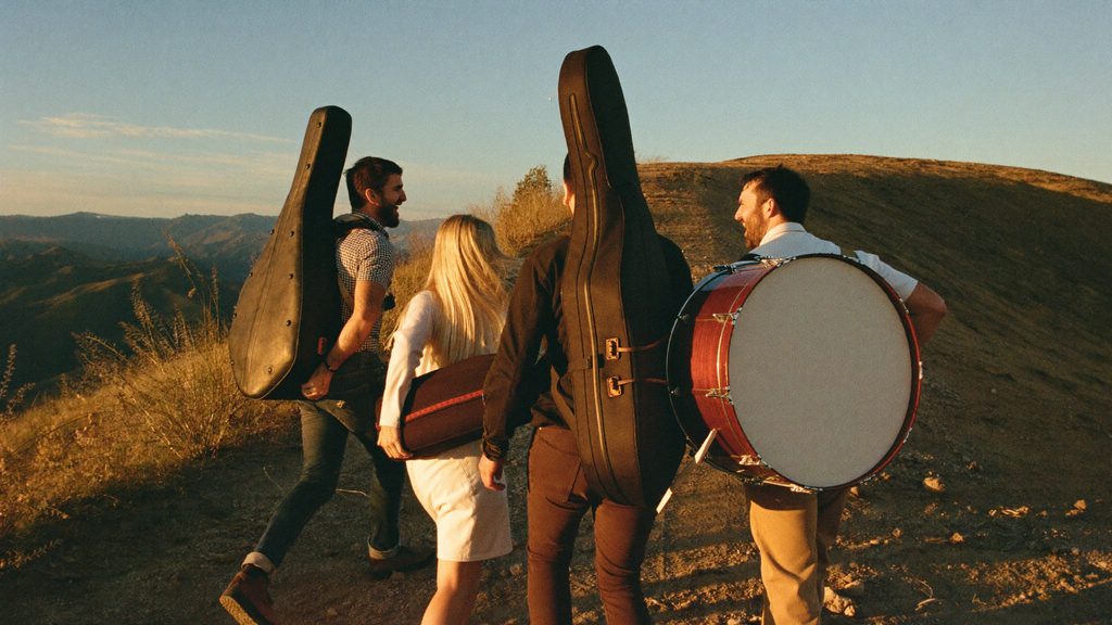 Trailfire carrying their instruments along a ridge at sunset